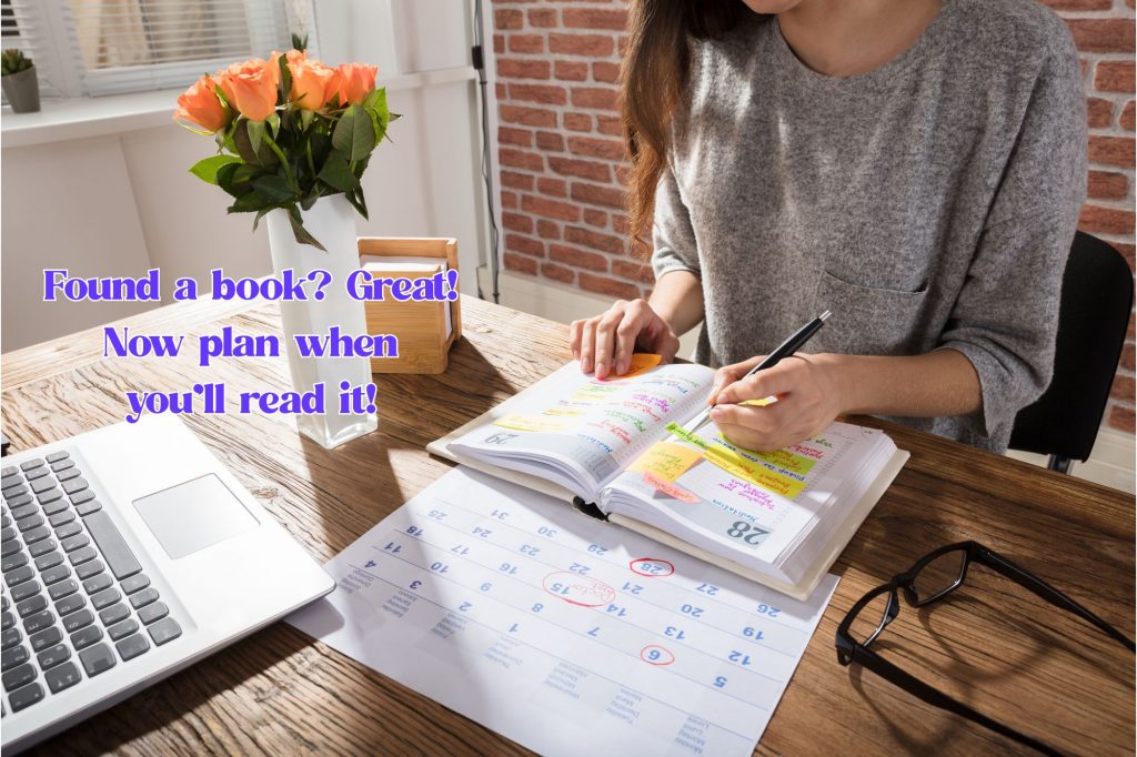 a woman writes in a planner with a calendar and laptop and text overlay reads "found a book? great! Now plan when you'll read it." 