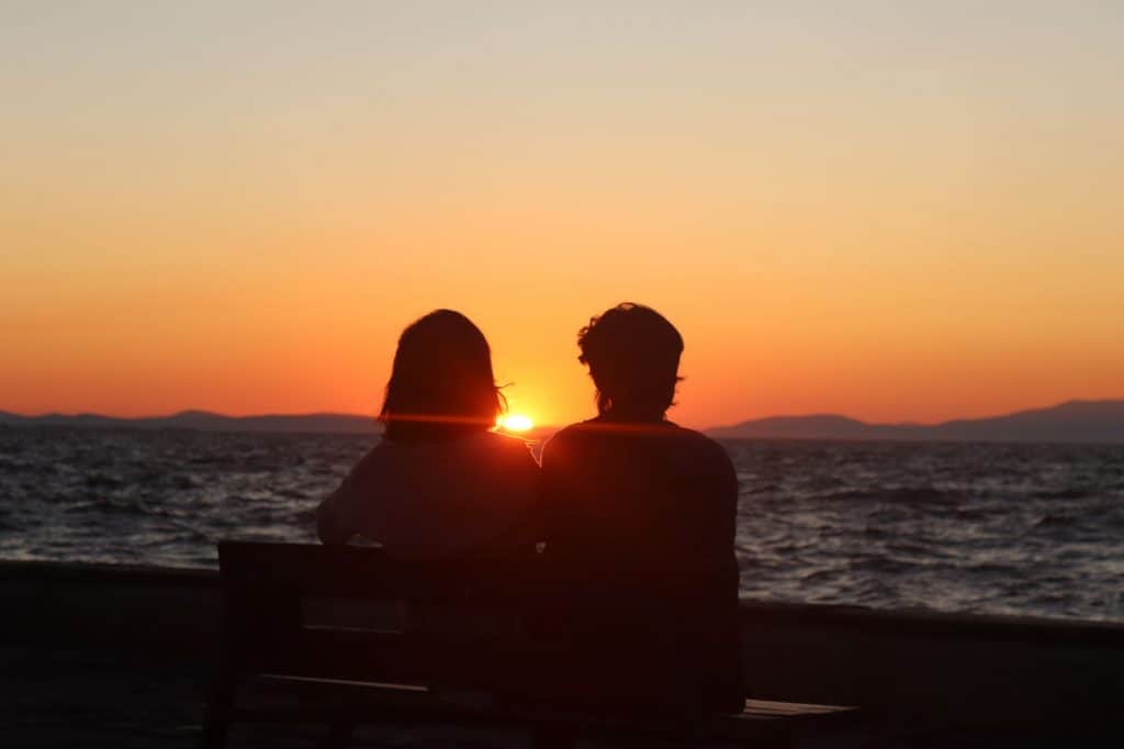 gender neutral couple in front of setting sun over water