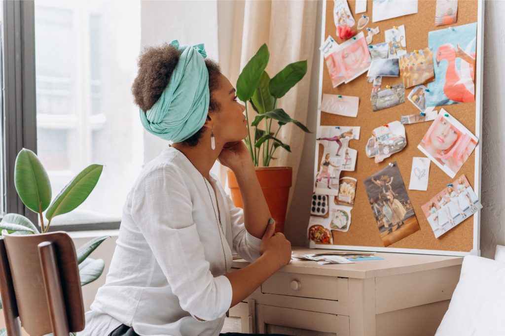 woman looks at vision board of goals