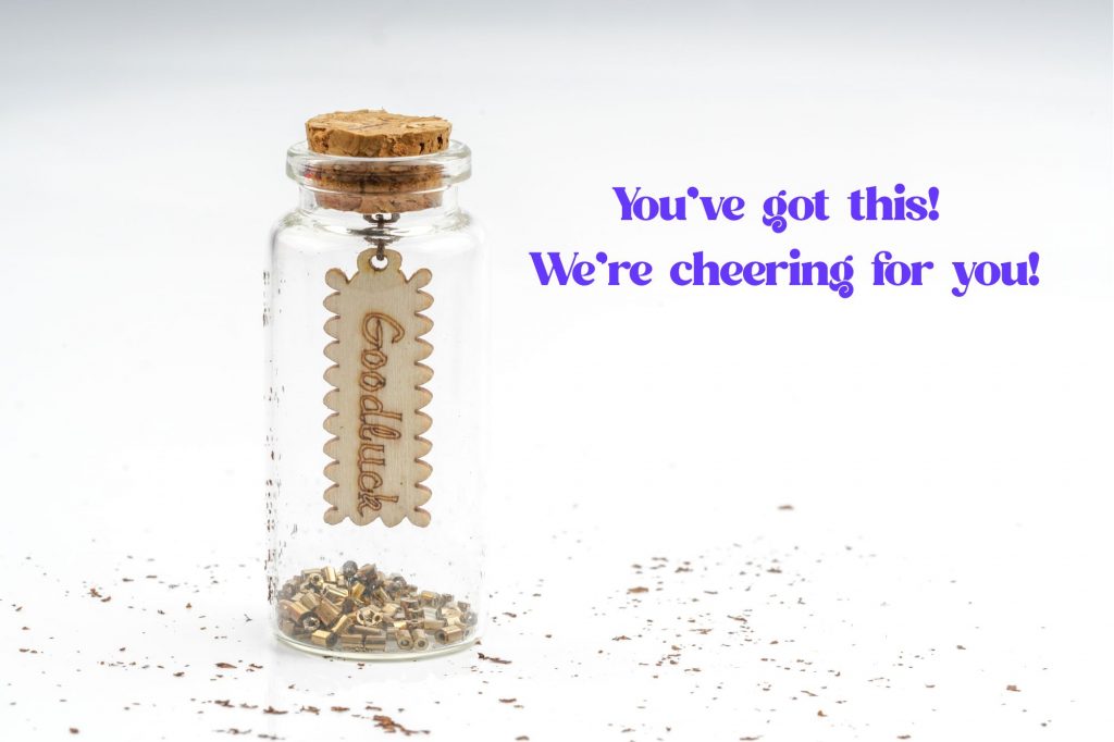 a little jar of glitter has a charm that has "goodluck" written on it. Text on the side reads "You've got this! We're cheering for you!" 