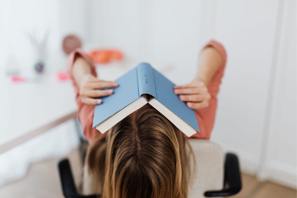 A woman has a book draped over her face 