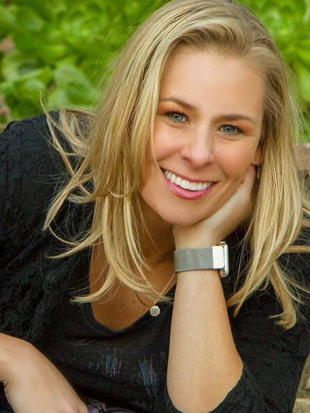 Mandie Brice's headshot. Mandie is leaning her elbow on her knee and resting her face in her hand with a smile