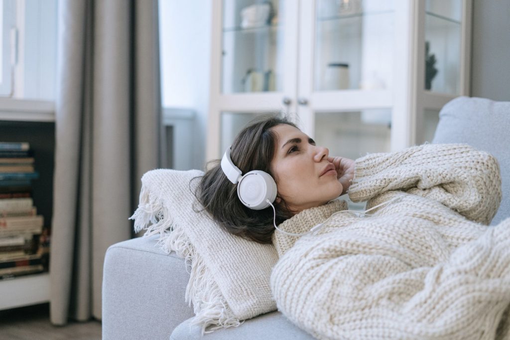 a woman is on a couch listening to headphones 
