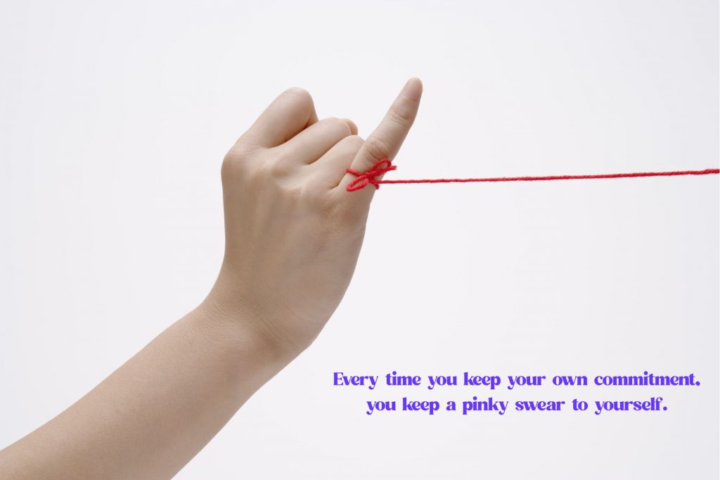 A woman's hand is center of the photo with pinky up and yarn tied to pinky with the text overlay that reads "every time you keep your own commitment, you keep a pinky swear to yourself." 